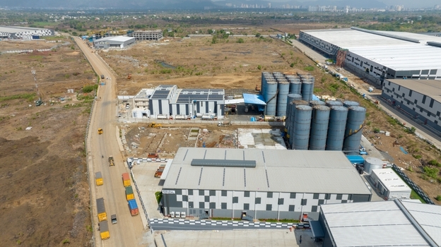 Aerial view of industrial warehouse complex with large storage silos modern buildings and trucks on an adjacent road in Bhiwandi Maharashtra India. Aerial view of industrial warehouse complex with large storage silos modern buildings and trucks on an adjacent road in Bhiwandi Maharashtra India.