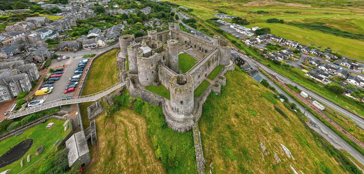 Aerial view of the medieval Castell Harlech with its stone towers and grassy courtyard overlooking the town and green hills in Harlech Wales United Kingdom.