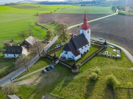 Aerial view of the historic Church of Saint Ladislaus with its red steeple and stone fortification wall surrounded by green fields in Liptovske Matiasovce Zilina Region Slovakia.