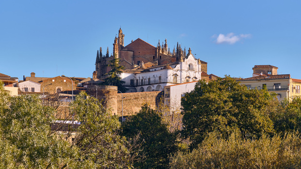 Plasencia Spain 03 December 2025 View of the Plasencia Cathedral complex with its gothic spires and stone walls rising above lush green trees under a clear blue sky. Plasencia Spain 03 December 2025 View of the Plasencia Cathedral complex with its gothic spires and stone walls rising above lush green trees under a clear blue sky.