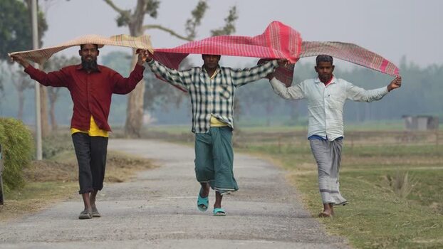 View of three men walking on a rural road with a sunshade Bangladesh.