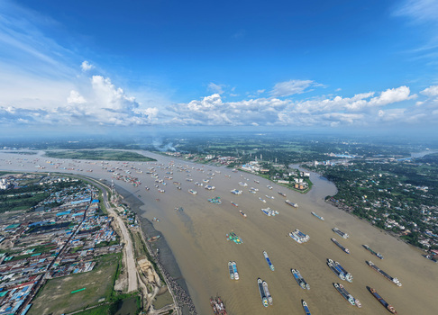 Aerial view of Karnaphuli River with numerous cargo ships and barges navigating the waterway surrounded by the urban landscape of Chattogram Chittagong Division Bangladesh.