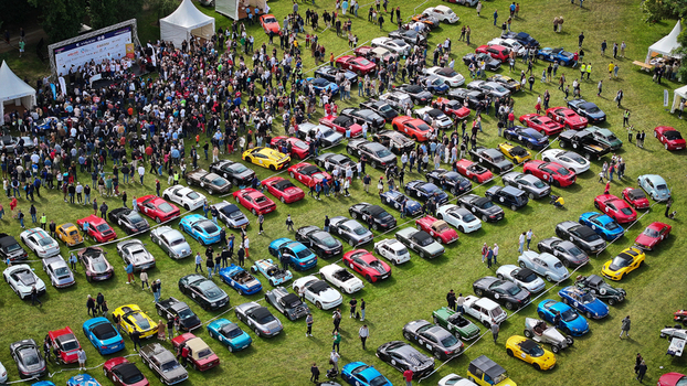 La Chapelle de Guinchay France 01 June 2024 Aerial view of a large gathering of classic and modern sports cars parked in rows on a green field during an outdoor automotive event.