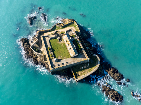 Aerial view of the ancient Fort National standing defiant against the turquoise sea an island fortress of weathered stone and emerald grass Saint Malo Brittany France. Aerial view of the ancient Fort National standing defiant against the turquoise sea an island fortress of weathered stone and emerald grass Saint Malo Brittany France.