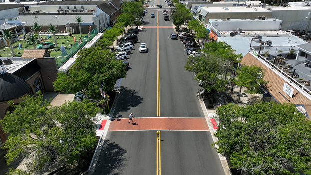 Aerial view of a quiet street in Stone Harbor with a pedestrian crossing lined with trees parked cars and local businesses in Stone Harbor New Jersey United States.