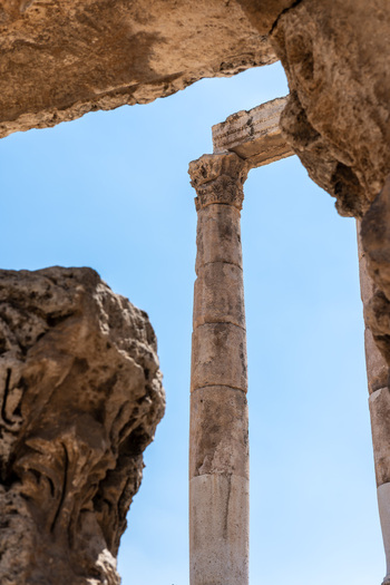 View of the ancient stone columns of the Amman Citadel framed by weathered rock formations under a clear blue sky in Amman Amman Governorate Jordan.