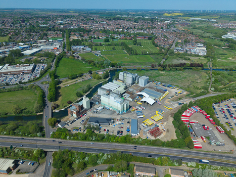 Aerial view of industrial buildings and warehouses near a winding river and green fields under a clear sky in Little Irchester England United Kingdom. Aerial view of industrial buildings and warehouses near a winding river and green fields under a clear sky in Little Irchester England United Kingdom.