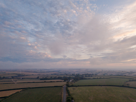Aerial view of the misty rural countryside near Looe featuring foggy fields agricultural farmland and a winding country road in Looe Cornwall United Kingdom. Aerial view of the misty rural countryside near Looe featuring foggy fields agricultural farmland and a winding country road in Looe Cornwall United Kingdom.