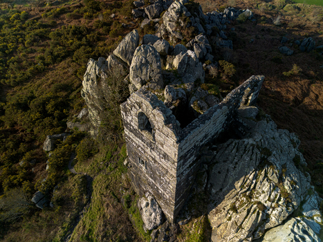 Aerial view of the historic Roche Rock chapel ruins perched atop a rugged granite outcrop surrounded by moorland in Roche Cornwall United Kingdom. Aerial view of the historic Roche Rock chapel ruins perched atop a rugged granite outcrop surrounded by moorland in Roche Cornwall United Kingdom.