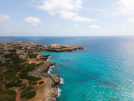 Aerial view of the coastal resort area with turquoise waters rocky cliffs and residential buildings under a blue sky in Sa Coma Balearic Islands Spain. Aerial view of the coastal resort area with turquoise waters rocky cliffs and residential buildings under a blue sky in Sa Coma Balearic Islands Spain.