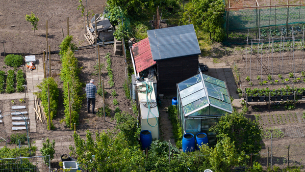 Aerial view of Amateur Gardeners Association Het Kloosterpark with a man working near a greenhouse and garden beds in De Bilt Utrecht Netherlands.