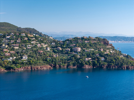 Aerial view of Le Trayas with Mediterranean villas on the hillside lush vegetation rocky red cliffs and the deep blue sea in Saint Raphael Provence Alpes Cote d Azur France. Aerial view of Le Trayas with Mediterranean villas on the hillside lush vegetation rocky red cliffs and the deep blue sea in Saint Raphael Provence Alpes Cote d Azur France.