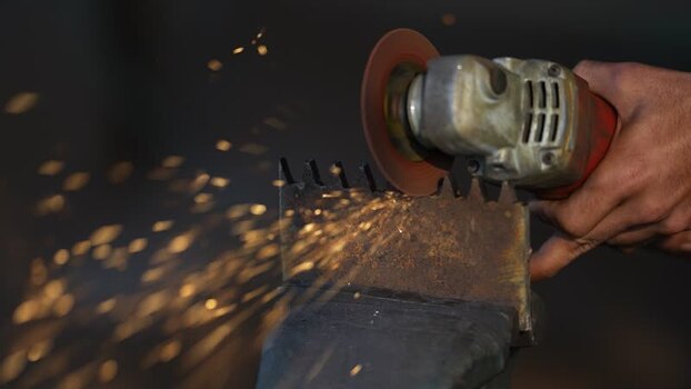 View of a worker using an angle grinder on metal in Bangladesh.