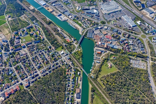 Aerial view of a waterway cutting through the urban sprawl and lush greenery near the roundabouts Sausheim Grand Est France.
