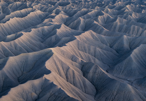 Aerial view of the intricate patterns of eroded badlands and sharp ridges under soft twilight in Hanksville Utah United States.
