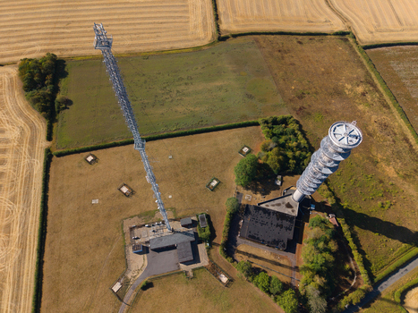 Aerial view of Morborne Hill Transmitter with its tall lattice mast and adjacent concrete tower surrounded by agricultural fields in Morborne England United Kingdom. Aerial view of Morborne Hill Transmitter with its tall lattice mast and adjacent concrete tower surrounded by agricultural fields in Morborne England United Kingdom.
