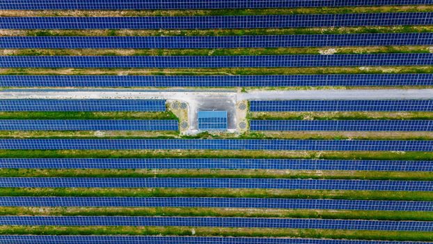 Aerial view of rows of blue solar panels in a large photovoltaic farm with a central utility building Sabac Vojvodina Serbia.