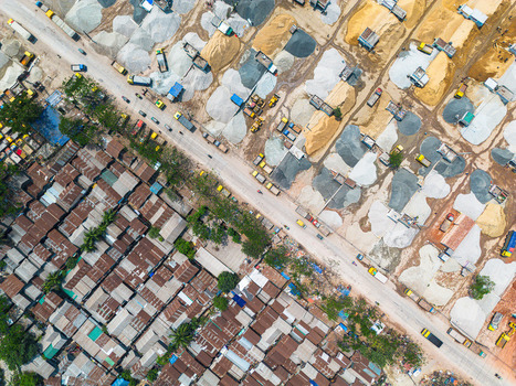 Aerial view of stark contrasts between neatly organized piles of construction materials and the dense chaotic patterns of a slum Dhaka Dhaka Division Bangladesh. Aerial view of stark contrasts between neatly organized piles of construction materials and the dense chaotic patterns of a slum Dhaka Dhaka Division Bangladesh.