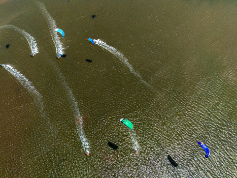 Aerial view of kitesurfers gliding across the water at Depok Beach leaving white wakes behind them in Special Region of Yogyakarta Indonesia.