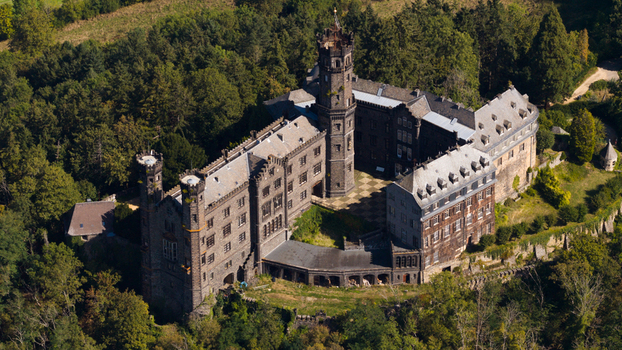Aerial view of Schaumburg Castle featuring stone towers and historic architecture surrounded by dense forest in Balduinstein Rheinland Pfalz Germany. Aerial view of Schaumburg Castle featuring stone towers and historic architecture surrounded by dense forest in Balduinstein Rheinland Pfalz Germany.