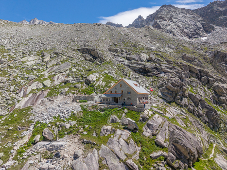 Aerial view of the Gelmerseehutte mountain refuge nestled among steep rocky slopes and alpine terrain in Guttannen Canton of Bern Switzerland.