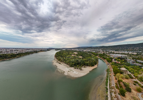 Aerial view of the sandy low water tip of Obudai sziget on the Danube with tree cover riverbanks and Budapest cityscape beneath dramatic summer clouds in Hungary. Aerial view of the sandy low water tip of Obudai sziget on the Danube with tree cover riverbanks and Budapest cityscape beneath dramatic summer clouds in Hungary.