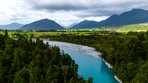 Aerial view of the Hokitika River s milky turquoise waters winding through dense green forests under a vast sky Hokitika Gorge West Coast Region New Zealand. Aerial view of the Hokitika River s milky turquoise waters winding through dense green forests under a vast sky Hokitika Gorge West Coast Region New Zealand.