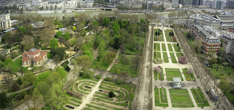 Aerial view of lush green gardens contrast with the Seine river and urban landscape in the distance Paris France.