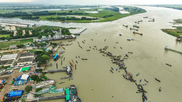 Baghabari Bangladesh 20 August 2022 Aerial view of the busy Baghabari river port with numerous boats and cargo vessels industrial facilities and green landscape.