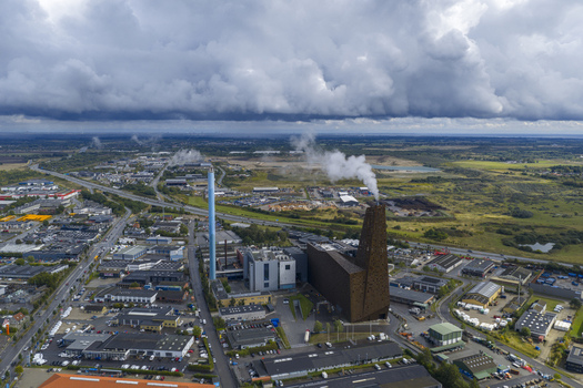 Aerial view of the Energitarnet waste to energy plant with its distinctive brown facade and smoking chimney under a dramatic cloudy sky in Roskilde Denmark. Aerial view of the Energitarnet waste to energy plant with its distinctive brown facade and smoking chimney under a dramatic cloudy sky in Roskilde Denmark.