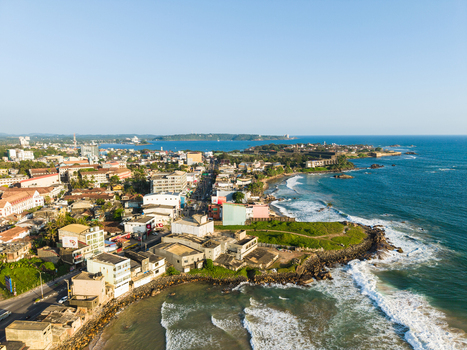 Aerial view of the historic Galle Fort and coastal buildings along the Indian Ocean shoreline under a clear blue sky in Galle Southern Province Sri Lanka.