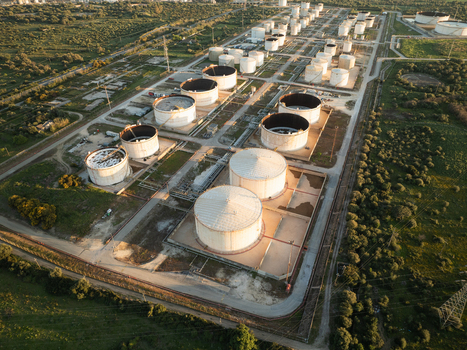Aerial view of an industrial oil refinery with large storage tanks surrounded by green vegetation in Augusta Sicily Italy. Aerial view of an industrial oil refinery with large storage tanks surrounded by green vegetation in Augusta Sicily Italy.