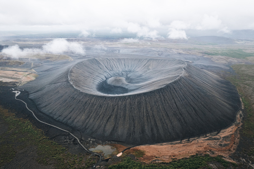 Aerial view of Hverfjall volcanic crater with its dark tephra slopes and surrounding lava fields under a cloudy sky in Thingeyjarsveit Iceland.