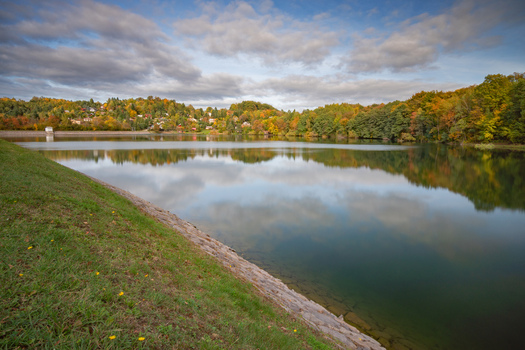 View of Velka Richnava Lake surrounded by autumn foliage and a stone embankment in Stiavnicke Bane Banska Bystrica Region Slovakia.