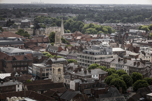 Aerial view of the historic city of York featuring dense medieval rooftops church towers and narrow streets under a soft overcast sky in York England United Kingdom.