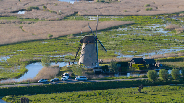 Aerial view of a traditional historic windmill at Kinderdijk surrounded by lush green wetlands and water channels in Kinderdijk South Holland Netherlands. Aerial view of a traditional historic windmill at Kinderdijk surrounded by lush green wetlands and water channels in Kinderdijk South Holland Netherlands.
