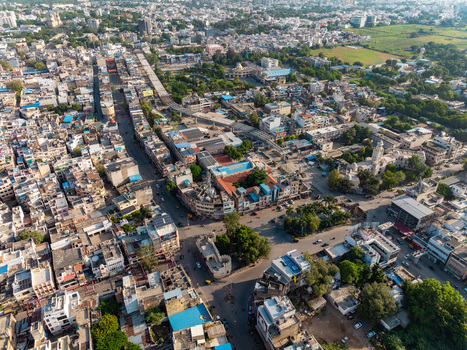 Aerial view of the dense urban landscape of Udaipur featuring historic buildings narrow streets and lush green trees in Udaipur Rajasthan India.