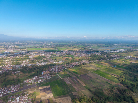 Aerial view of the city of Malang surrounded by lush green rice paddies agricultural fields and residential areas in Malang East Java Indonesia. Aerial view of the city of Malang surrounded by lush green rice paddies agricultural fields and residential areas in Malang East Java Indonesia.