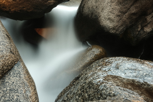 View of Sequoia National Park with a long exposure of silky water cascading between smooth granite boulders Tulare County California United States. View of Sequoia National Park with a long exposure of silky water cascading between smooth granite boulders Tulare County California United States.