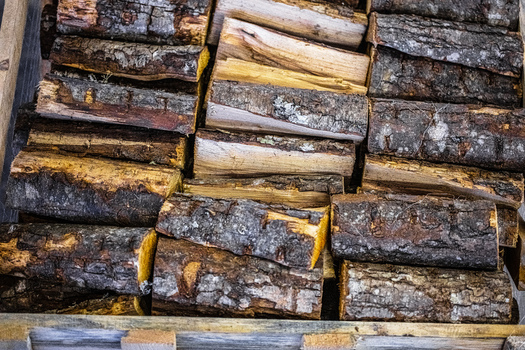 View of stacked firewood logs with rough bark and textured wood grain in Latvia. View of stacked firewood logs with rough bark and textured wood grain in Latvia.