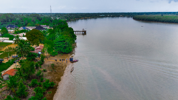 Aerial view of the riverbank with lush greenery a small wooden pier and boats moored along the shore in Minima Rivers Nigeria.