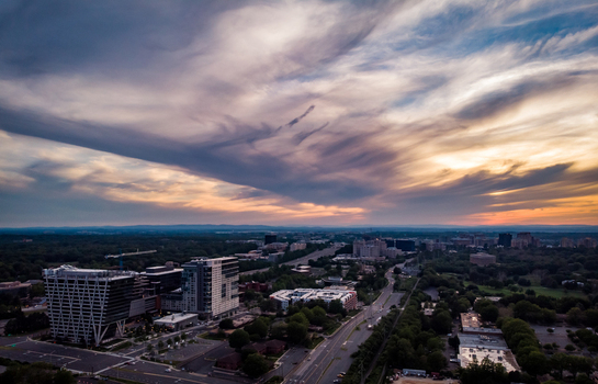 Reston Virginia United States 27 May 2020 Aerial view of modern office buildings and roads surrounded by lush greenery under a dramatic sunset sky. Reston Virginia United States 27 May 2020 Aerial view of modern office buildings and roads surrounded by lush greenery under a dramatic sunset sky.
