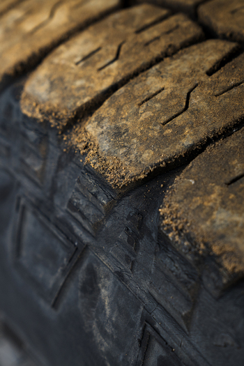 View of the worn tire tread textured with grime and grit against the dark rubber hinting at journeys through rugged landscapes Skaftárhreppur Iceland. View of the worn tire tread textured with grime and grit against the dark rubber hinting at journeys through rugged landscapes Skaftárhreppur Iceland.