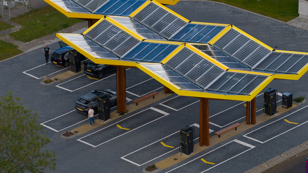 Oostzaan Netherlands 09 June 2026 Aerial view of the Fastned charging station with solar panel roof electric vehicles parked at charging points and people walking.
