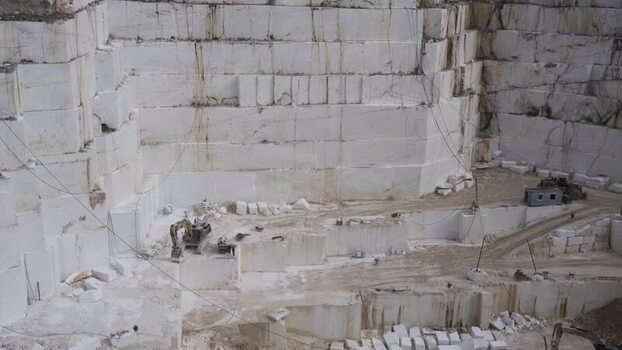 View of a white marble quarry with excavators and stone walls Greece.