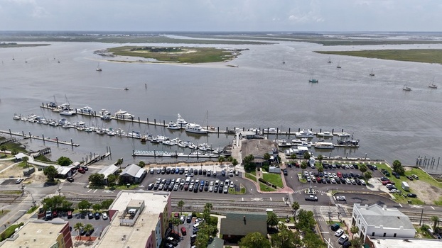 Aerial view of a bustling marina with white boats colorful urban buildings and a wide river flowing to green marshlands Fernandina Beach Florida United States. Aerial view of a bustling marina with white boats colorful urban buildings and a wide river flowing to green marshlands Fernandina Beach Florida United States.