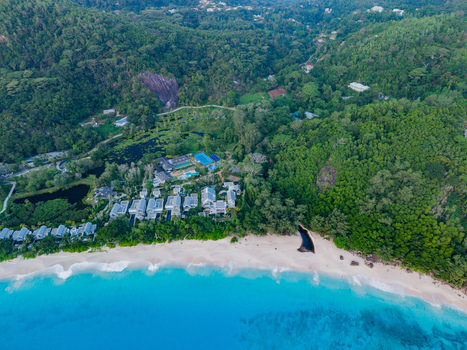 Aerial view of turquoise waves crash against the sandy shore meeting the lush green forests and buildings nestled inland Quatre Bornes Mahe Island Seychelles. Aerial view of turquoise waves crash against the sandy shore meeting the lush green forests and buildings nestled inland Quatre Bornes Mahe Island Seychelles.