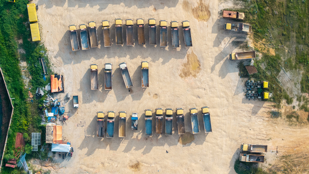 Aerial view of a construction site with rows of parked dump trucks on a sandy ground in Bukit Tambun Penang Malaysia. Aerial view of a construction site with rows of parked dump trucks on a sandy ground in Bukit Tambun Penang Malaysia.