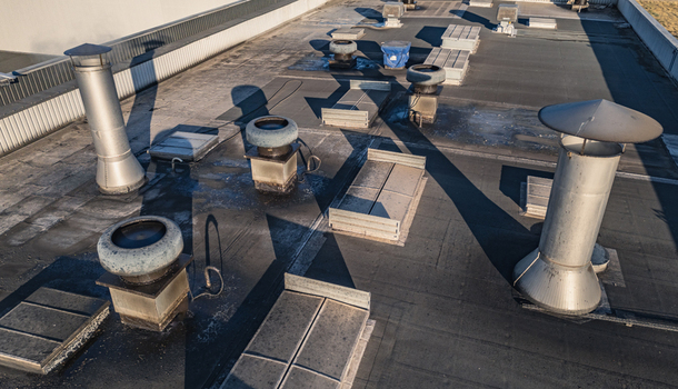 Aerial view of an industrial building rooftop featuring various ventilation systems exhaust fans and metal chimneys in Le Pouzin Auvergne Rhone Alpes France.