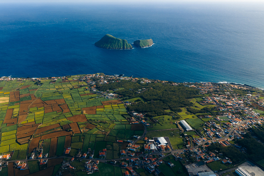 Aerial view of Pico Dona Joana geodesico overlooking the patchwork fields and the coastline with the Ilheus das Cabras islets in the distance Feteira Acores Portugal.